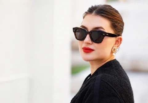 Portrait de profil d'une femme élégante portant des lunettes de soleil Ray-Ban tendance en acétate écaille de tortue foncé avec verres noirs chez Optical Gallery.