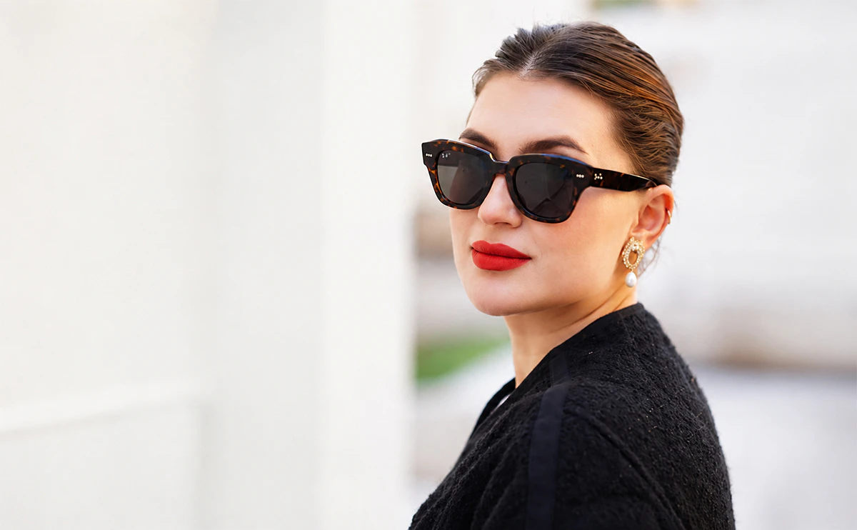 Portrait de profil d'une femme élégante portant des lunettes de soleil Ray-Ban tendance en acétate écaille de tortue foncé avec verres noirs chez Optical Gallery.