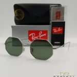 Lunettes de soleil géométriques octogonales Ray-Ban RB1972 dorées avec verres verts, présentées avec leur étui en cuir marron et le logo Optical Gallery.