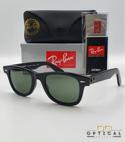 Lunettes de soleil Ray-Ban Wayfarer RB2140 noires avec verres verts G-15, présentées avec leur étui noir, leur boîte grise et leur kit de nettoyage, le tout sur fond blanc avec le logo Optical Gallery.