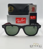Lunettes de soleil Ray-Ban Wayfarer RB2140 noires avec verres verts G-15, présentées avec leur étui noir, leur boîte grise et leur kit de nettoyage, le tout sur fond blanc avec le logo Optical Gallery.