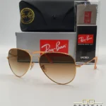 Lunettes de soleil Ray-Ban Aviator RB3025 monture métallique or rose avec verres dégradés marrons, étui et boîte d'origine.