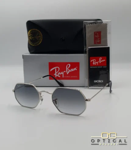 Lunettes de soleil Ray-Ban Octagonal RB3556 argentées avec verres dégradés gris, étui noir, boîte grise et accessoires.