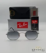Lunettes de soleil Ray-Ban Octagonal RB3556 argentées avec verres dégradés gris, étui noir, boîte grise et accessoires.