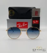 Lunettes de soleil Ray-Ban Jack RB3565 dorées avec verres dégradés bleus, étui noir, boîte grise et livret de garantie chez Optical Gallery.