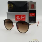 Lunettes de soleil Ray-Ban Scuderia Ferrari RB3602M noires et dorées avec verres dégradés marrons, étui noir, boîte grise et livret de garantie chez Optical Gallery.