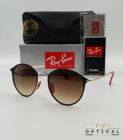Lunettes de soleil Ray-Ban Scuderia Ferrari RB3602M noires et dorées avec verres dégradés marrons, étui noir, boîte grise et livret de garantie chez Optical Gallery.