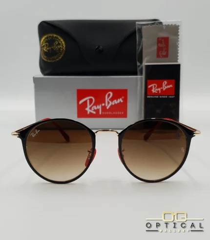 Lunettes de soleil Ray-Ban Scuderia Ferrari RB3602M noires et dorées avec verres dégradés marrons, étui noir, boîte grise et livret de garantie chez Optical Gallery.