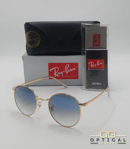 Lunettes de soleil Ray-Ban New Round RB3637 dorées avec verres dégradés bleus gris, étui noir, boîte grise et livret de garantie chez Optical Gallery.