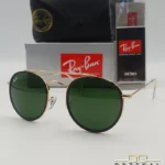Lunettes de soleil Ray-Ban Round Double Bridge RB3647N dorées avec cerclages en acétate noir et verres verts G-15, étui noir, boîte grise et livret de garantie chez Optical Gallery.