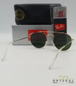 Lunettes de soleil Ray-Ban Round Double Bridge RB3647N dorées avec cerclages en acétate noir et verres verts G-15, étui noir, boîte grise et livret de garantie chez Optical Gallery.
