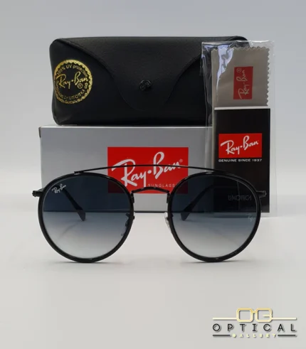 Lunettes de soleil Ray-Ban Round Double Bridge RB3647N noires avec cerclages en acétate noir et verres dégradés bleus gris, étui noir, boîte grise et livret de garantie chez Optical Gallery.