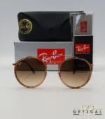 Lunettes de soleil Ray-Ban Round Double Bridge RB3647N marrons avec cerclages en acétate transparent marron et verres dégradés marrons, étui noir, boîte grise et livret de garantie chez Optical Gallery.