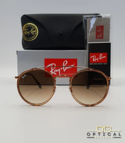 Lunettes de soleil Ray-Ban Round Double Bridge RB3647N marrons avec cerclages en acétate transparent marron et verres dégradés marrons, étui noir, boîte grise et livret de garantie chez Optical Gallery.