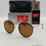 Lunettes de soleil Ray-Ban Round Double Bridge RB3647N dorées avec cerclages en acétate marron et verres marrons B-15, étui noir, boîte grise et livret de garantie chez Optical Gallery.