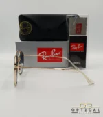Lunettes de soleil Ray-Ban Round Double Bridge RB3647N dorées avec cerclages en acétate transparent et verres dégradés bleus, étui noir, boîte grise et livret de garantie chez Optical Gallery.