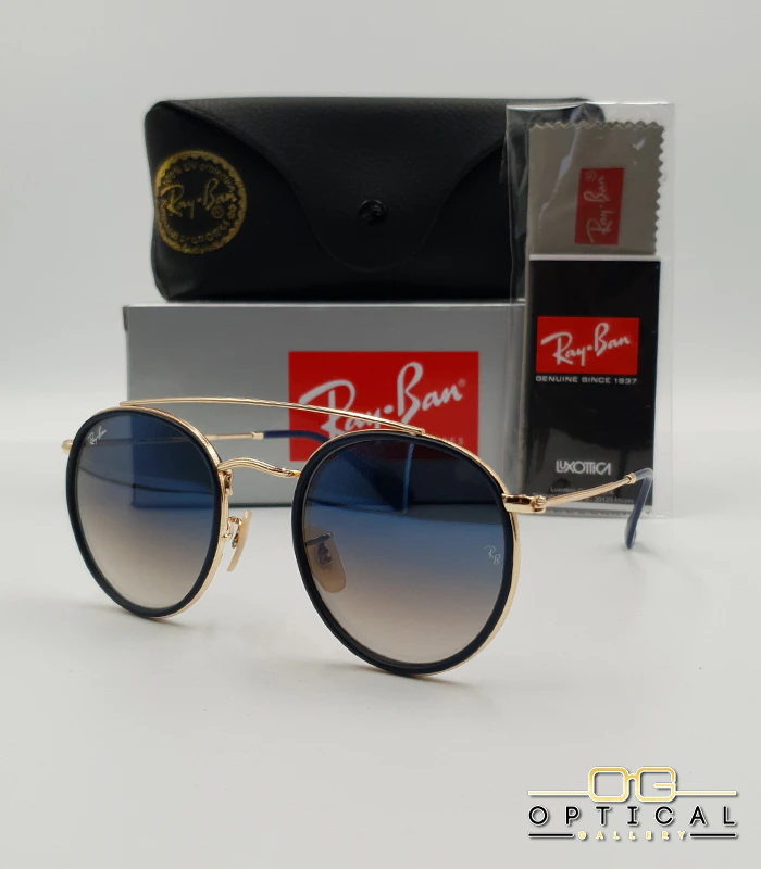 lunettes-de-soleil-ray-ban-round-double-bridge-rb3647n-or-bleu-marine-degrade-optical-gallery Lunettes de soleil Ray-Ban Round Double Bridge RB3647N dorées avec cerclages en acétate bleu marine et verres dégradés bleus marrons, étui noir, boîte grise et livret de garantie chez Optical Gallery.