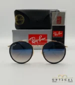 Lunettes de soleil Ray-Ban Round Double Bridge RB3647N dorées avec cerclages en acétate bleu marine et verres dégradés bleus marrons, étui noir, boîte grise et livret de garantie chez Optical Gallery.