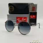 Lunettes de soleil Ray-Ban Round Double Bridge RB3647N gris anthracite avec cerclages en acétate transparent et verres dégradés bleus, étui noir, boîte grise et livret de garantie chez Optical Gallery.