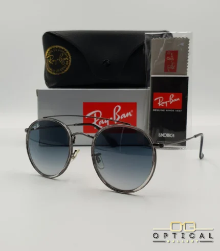 Lunettes de soleil Ray-Ban Round Double Bridge RB3647N gris anthracite avec cerclages en acétate transparent et verres dégradés bleus, étui noir, boîte grise et livret de garantie chez Optical Gallery.