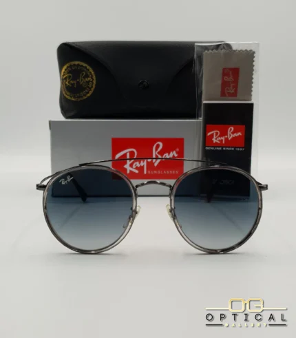Lunettes de soleil Ray-Ban Round Double Bridge RB3647N gris anthracite avec cerclages en acétate transparent et verres dégradés bleus, étui noir, boîte grise et livret de garantie chez Optical Gallery.