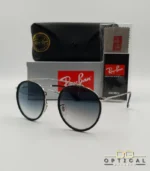 Lunettes de soleil Ray-Ban Round Double Bridge RB3647N argentées avec cerclages en acétate noir et verres dégradés bleus gris, étui noir, boîte grise et livret de garantie chez Optical Gallery.