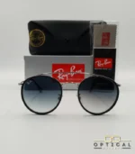 Lunettes de soleil Ray-Ban Round Double Bridge RB3647N argentées avec cerclages en acétate noir et verres dégradés bleus gris, étui noir, boîte grise et livret de garantie chez Optical Gallery.