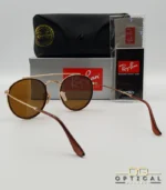 Lunettes de soleil Ray-Ban Round Double Bridge RB3647N dorées avec cerclages en acétate marron et verres marrons B-15, étui noir, boîte grise et livret de garantie chez Optical Gallery.