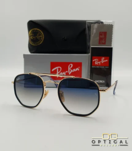 Lunettes de soleil Ray-Ban Marshal II RB3648M dorées avec cerclages en acétate bleu marine et verres dégradés bleus gris, étui noir, boîte grise et livret de garantie chez Optical Gallery.
