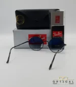 Voici les métadonnées entièrement optimisées pour cette nouvelle fiche produit de votre catalogue Ray-Ban (ray-ban-oval-rb1970-argent-lunettes-de-soleil-7.webp). Ce visuel présente une magnifique variante sombre et métallisée avec des verres dégradés, idéale pour enrichir votre catalogue. Paramètres de l'image : ray-ban-oval-rb1970-argent-lunettes-de-soleil-7.webp (Photo Produit Catalogue / Lunettes de Soleil Ray-Ban) Texte alternatif : Lunettes de soleil rondes Ray-Ban RB1970 avec monture en métal noir ou argent foncé et verres dégradés bleus, présentées avec l'étui officiel et le logo Optical Gallery.
