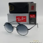 Voici les métadonnées entièrement optimisées pour cette nouvelle fiche produit de votre catalogue Ray-Ban (ray-ban-oval-rb1970-argent-lunettes-de-soleil-7.webp). Ce visuel présente une magnifique variante sombre et métallisée avec des verres dégradés, idéale pour enrichir votre catalogue. Paramètres de l'image : ray-ban-oval-rb1970-argent-lunettes-de-soleil-7.webp (Photo Produit Catalogue / Lunettes de Soleil Ray-Ban) Texte alternatif : Lunettes de soleil rondes Ray-Ban RB1970 avec monture en métal noir ou argent foncé et verres dégradés bleus, présentées avec l'étui officiel et le logo Optical Gallery.