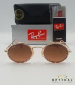 Lunettes de soleil Ray-Ban Round Double Bridge RB3847N dorées avec cerclages en acétate rose transparent et verres dégradés marrons, étui noir, boîte grise et livret de garantie chez Optical Gallery.