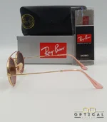 Lunettes de soleil Ray-Ban Round Double Bridge RB3847N dorées avec cerclages en acétate rose transparent et verres dégradés marrons, étui noir, boîte grise et livret de garantie chez Optical Gallery.