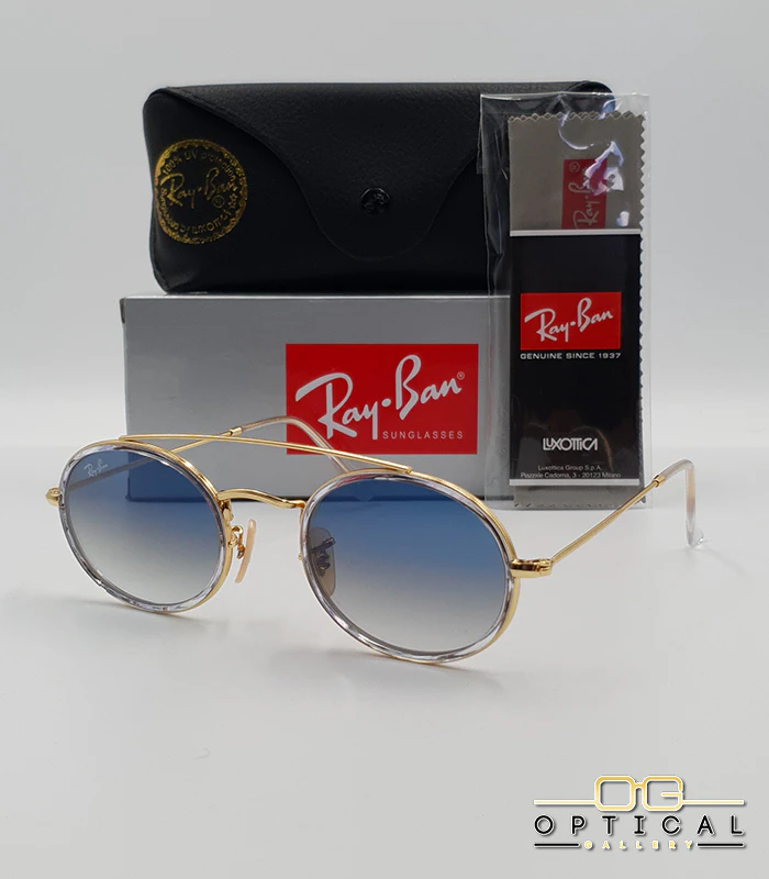 lunettes-de-soleil-ray-ban-round-double-bridge-rb3847n-or-transparent-bleu-degrade-optical-gallery Lunettes de soleil Ray-Ban Round Double Bridge RB3847N dorées avec cerclages en acétate transparent et verres dégradés bleus gris, étui noir, boîte grise et livret de garantie chez Optical Gallery.