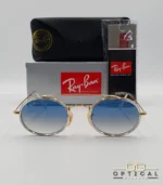Lunettes de soleil Ray-Ban Round Double Bridge RB3847N dorées avec cerclages en acétate transparent et verres dégradés bleus gris, étui noir, boîte grise et livret de garantie chez Optical Gallery.