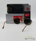 Lunettes de soleil Ray-Ban Round Double Bridge RB3847N dorées avec cerclages en acétate écaille de tortue et verres verts G-15, étui noir, boîte grise et livret de garantie chez Optical Gallery.