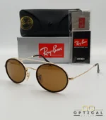 Lunettes de soleil Ray-Ban Round Double Bridge RB3847N dorées avec cerclages en acétate noir et verres marrons B-15, étui noir, boîte grise et livret de garantie chez Optical Gallery.