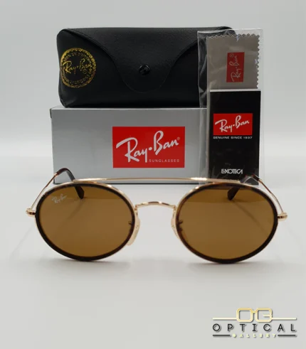 Lunettes de soleil Ray-Ban Round Double Bridge RB3847N dorées avec cerclages en acétate noir et verres marrons B-15, étui noir, boîte grise et livret de garantie chez Optical Gallery.