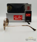 Lunettes de soleil Ray-Ban Round Double Bridge RB3847N dorées avec cerclages en acétate noir et verres marrons B-15, étui noir, boîte grise et livret de garantie chez Optical Gallery.