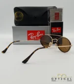 Lunettes de soleil Ray-Ban Round Double Bridge RB3847N dorées avec cerclages en acétate noir et verres marrons B-15, étui noir, boîte grise et livret de garantie chez Optical Gallery.